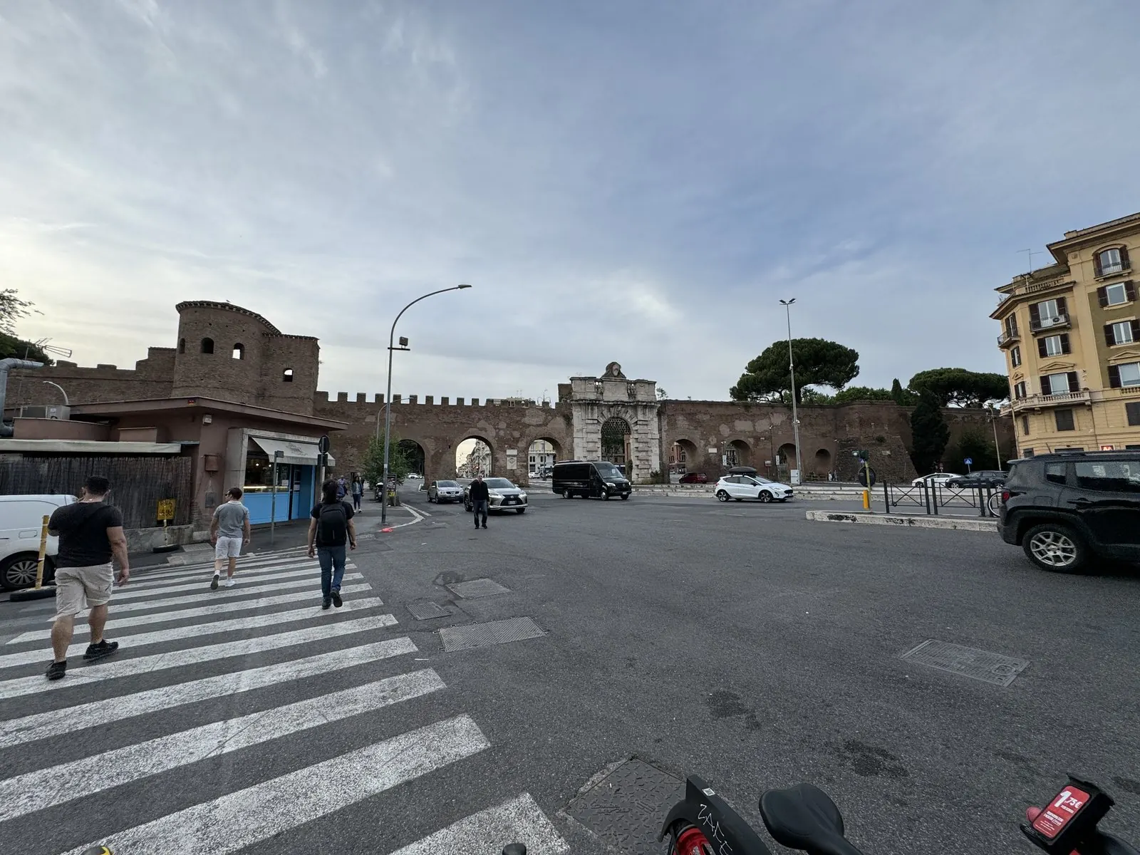 The Aurelian Wall and the gate of Porta San Giovanni across a wide Roman crossing in evening light