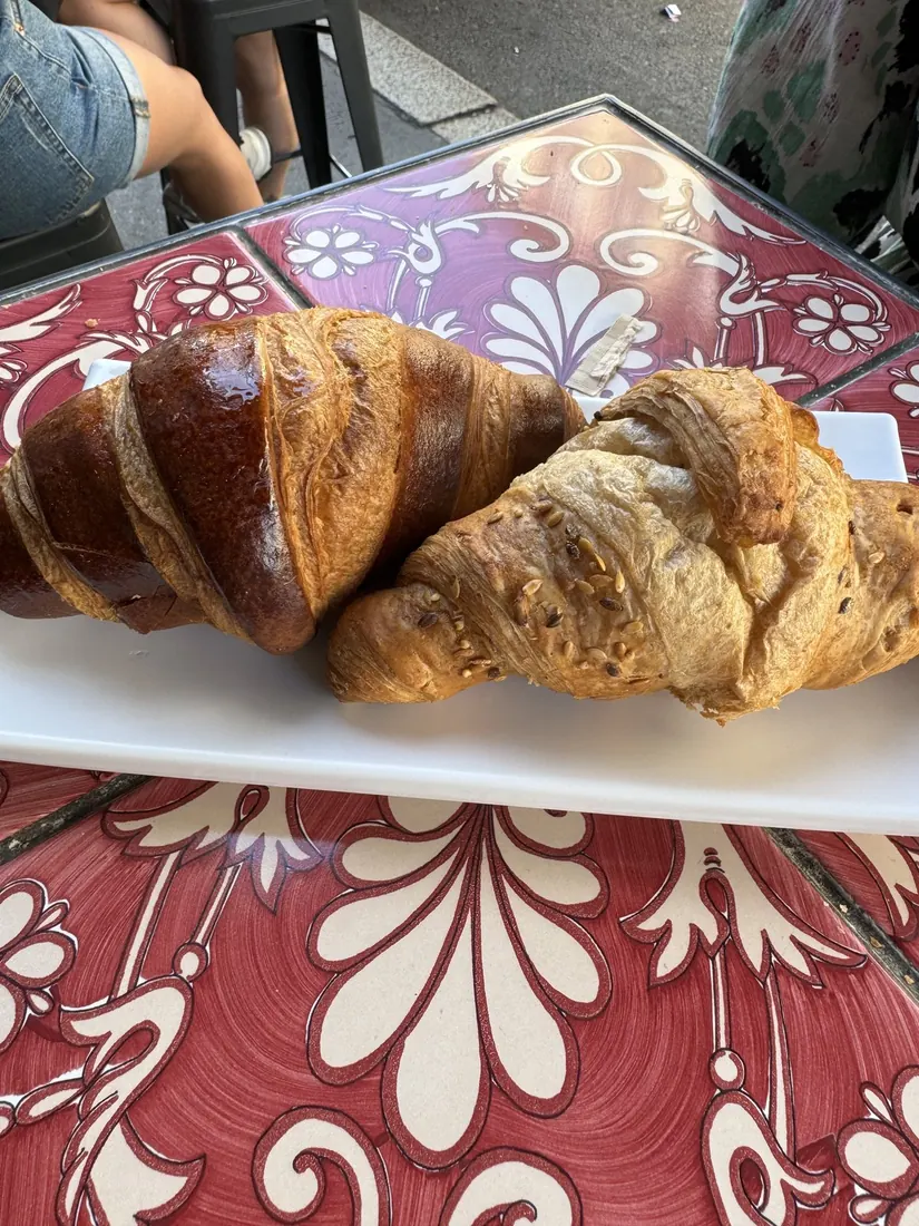 Two croissants on a plate on a red and white tiled café table