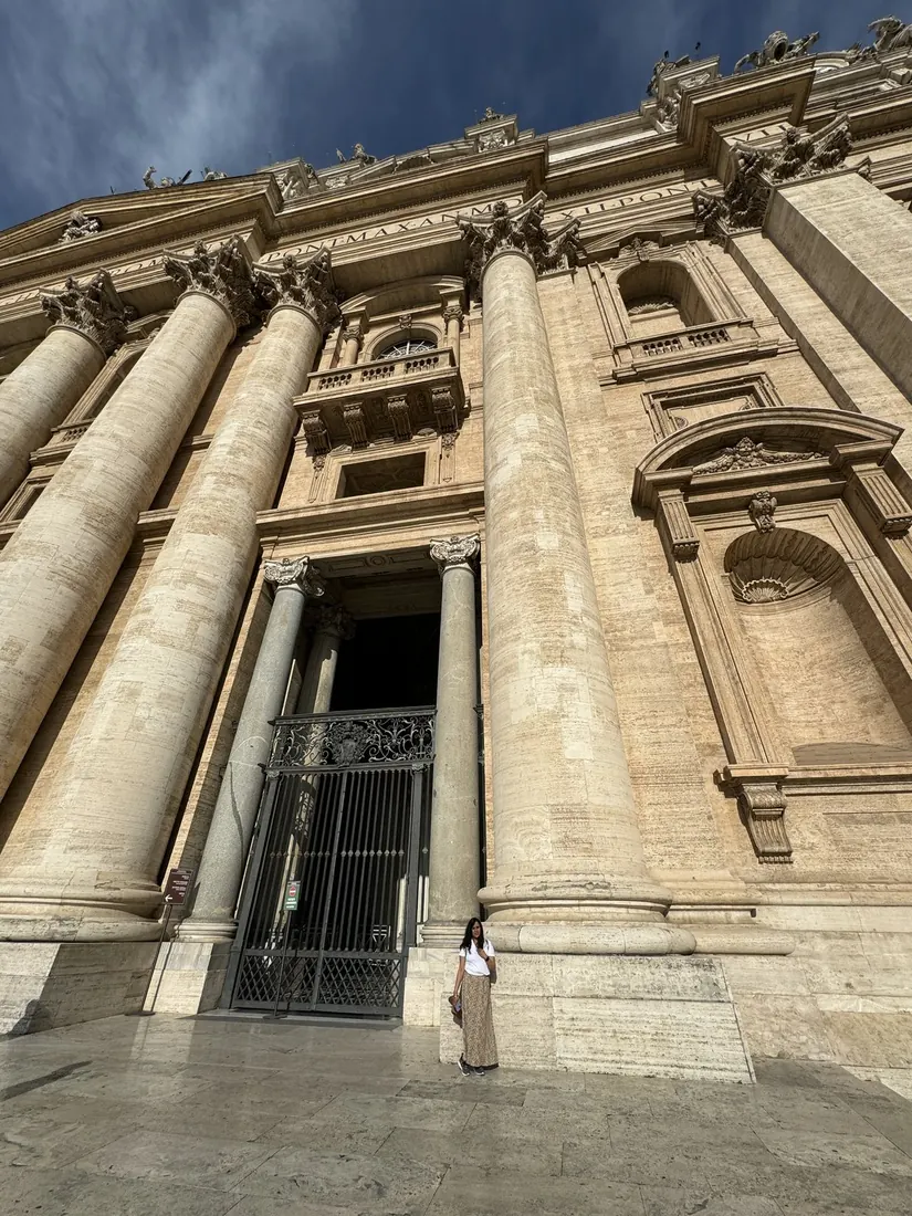Arsha, tiny, at the base of a giant column at the entrance of St. Peter's Basilica