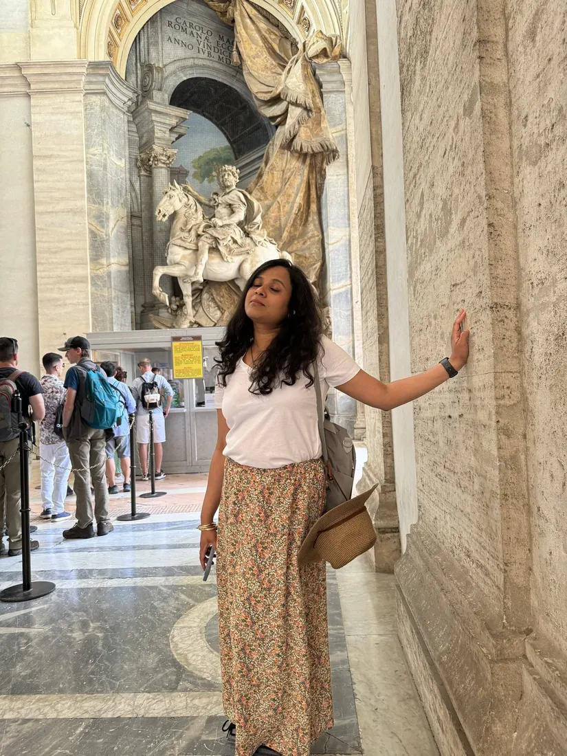 Arsha leaning on a huge marble pilaster, a marble statue of Charlemagne on horseback behind her
