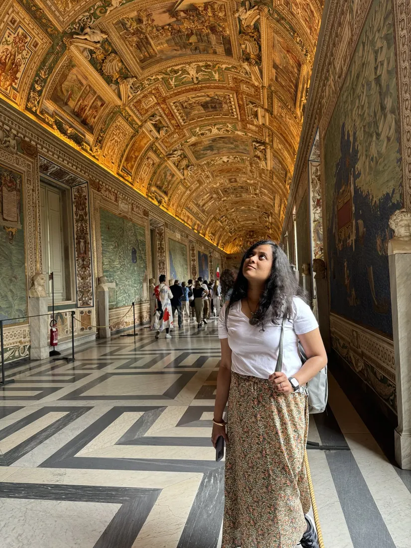 Arsha gazing up in the Gallery of Maps under a golden painted ceiling