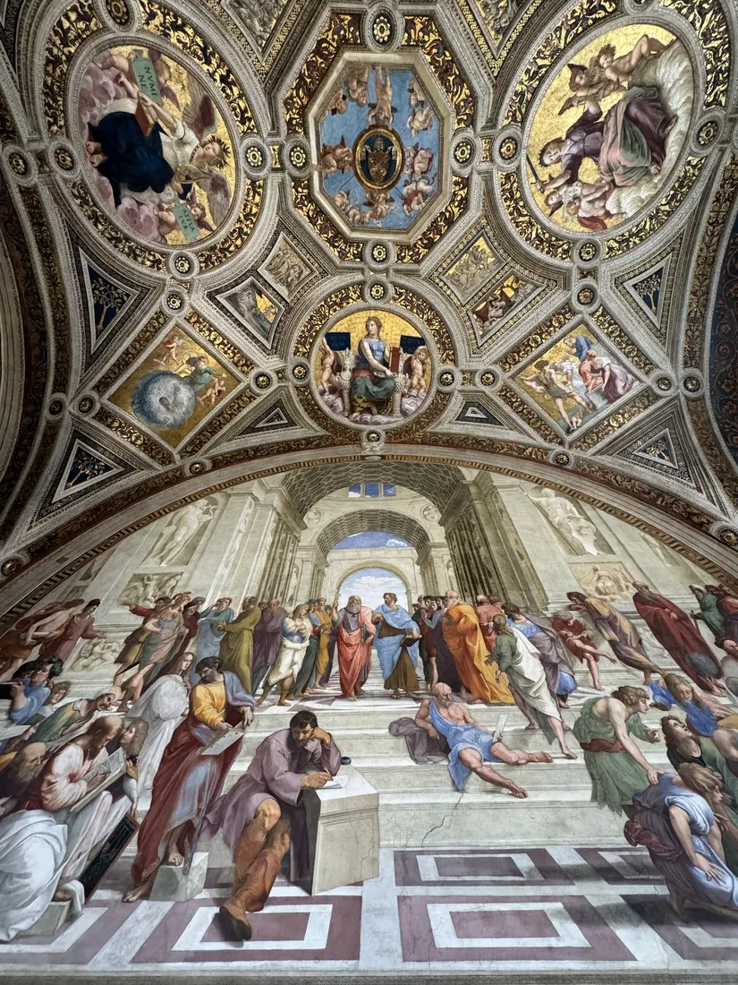 Raphael's School of Athens fresco below a painted ceiling in the Raphael Rooms