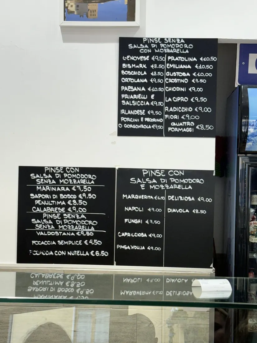 Two blackboards listing pinsa and pizza by the slice at Bonci's Pizzarium
