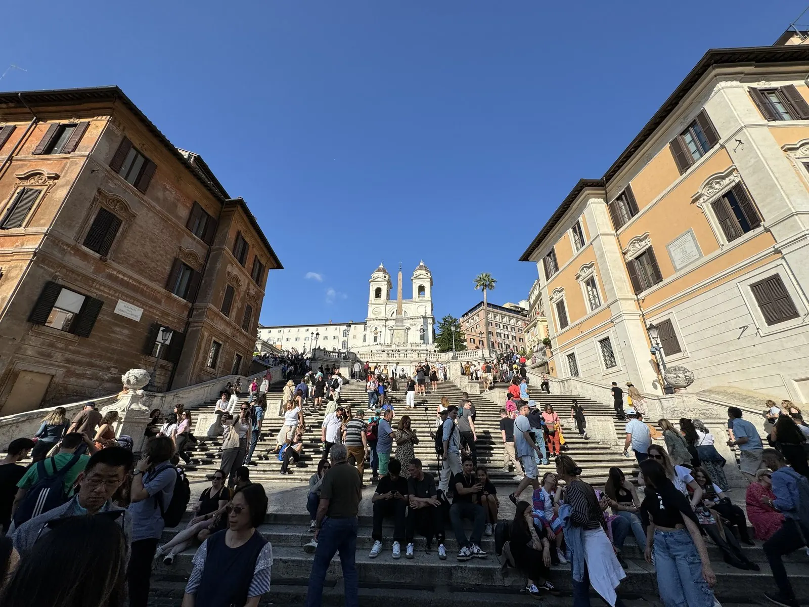 The Spanish Steps crowded with people under a deep blue sky, the church of Trinità dei Monti at the top