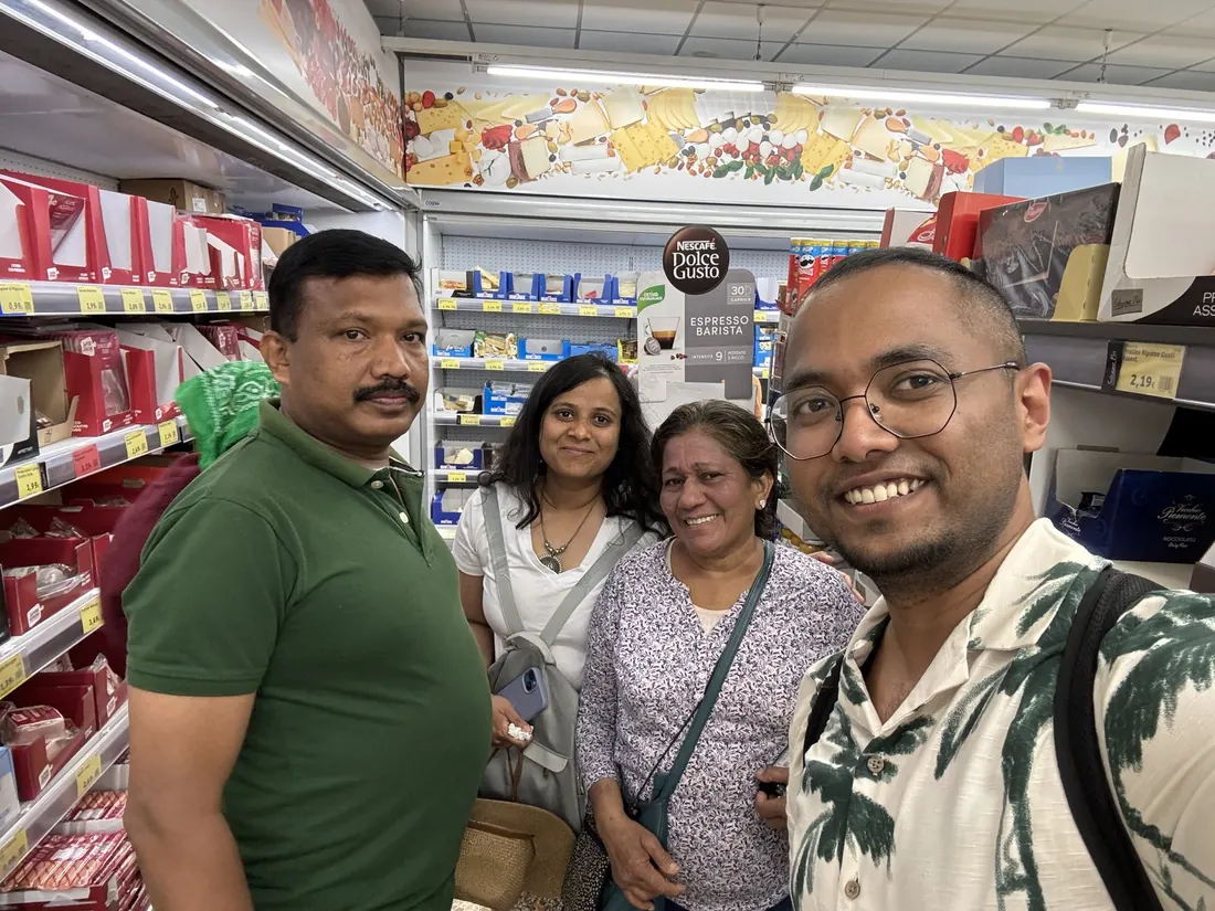 Binu, Arsha, Celine Auntie and a young man smiling together in a grocery store aisle
