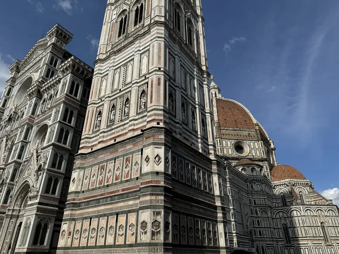 Giotto's bell tower in striped marble beside the cathedral, against a blue sky