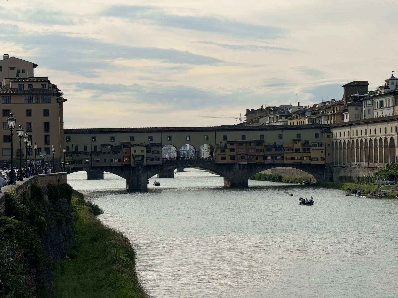 The Ponte Vecchio across the Arno, its houses and shops built along the bridge, under a soft evening sky