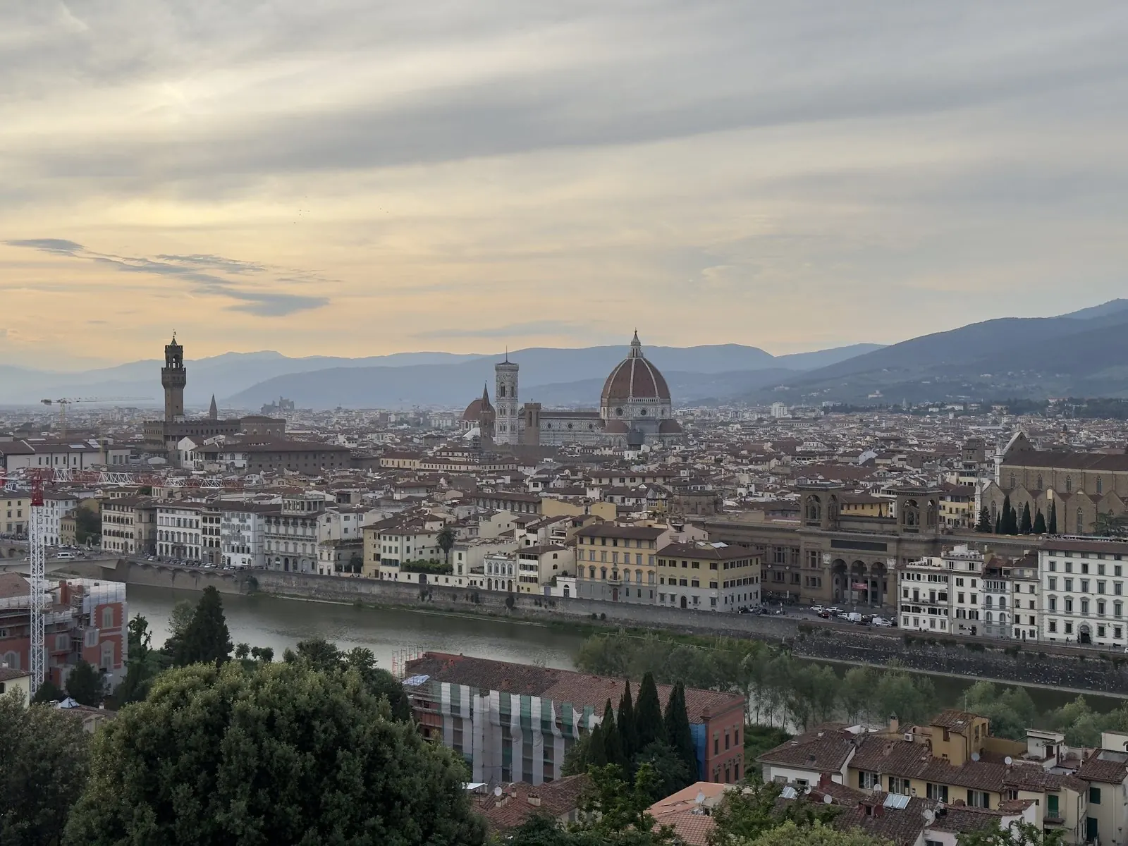 Florence from Piazzale Michelangelo at golden hour: the Duomo rising out of red roofs, the Arno, and Tuscan hills behind