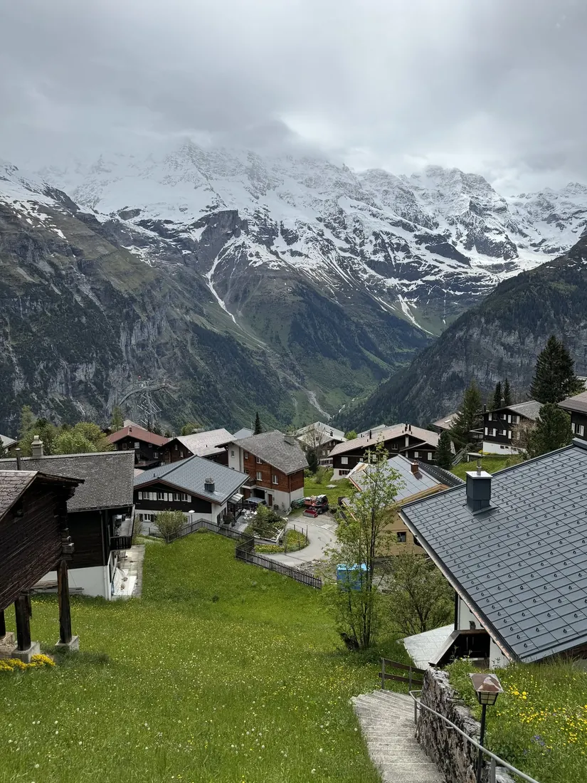 Mürren's chalets on a green ledge above a deep valley with snowy peaks