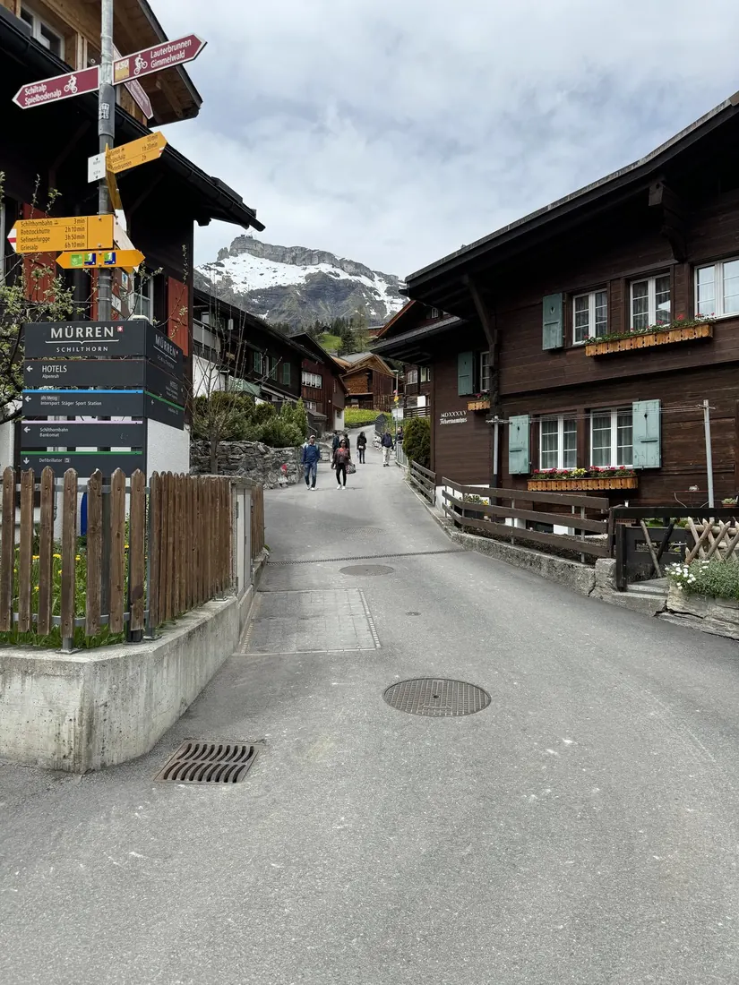 A Mürren street with wooden chalets and yellow hiking signposts