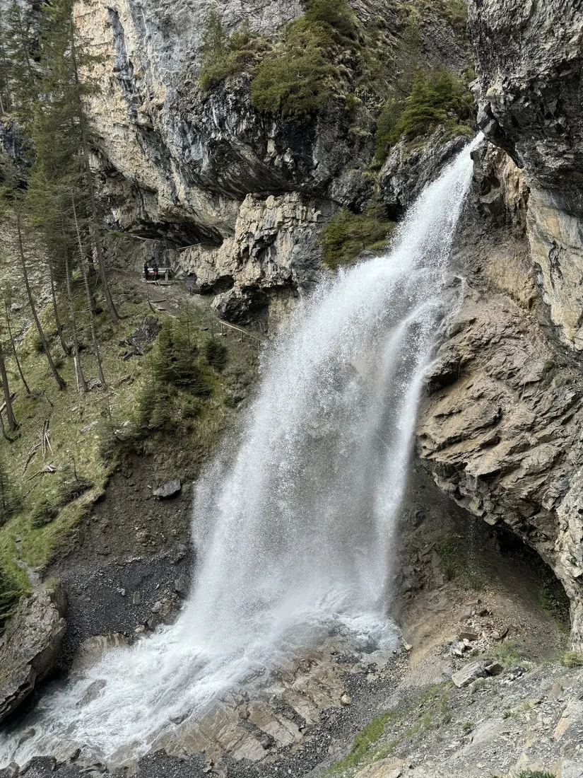 A glacial waterfall pouring down a rock face beside the trail