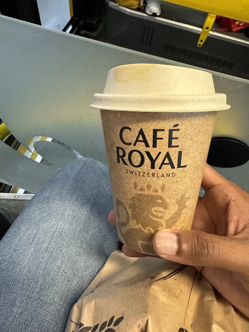 A Café Royal takeaway coffee cup held up on the train