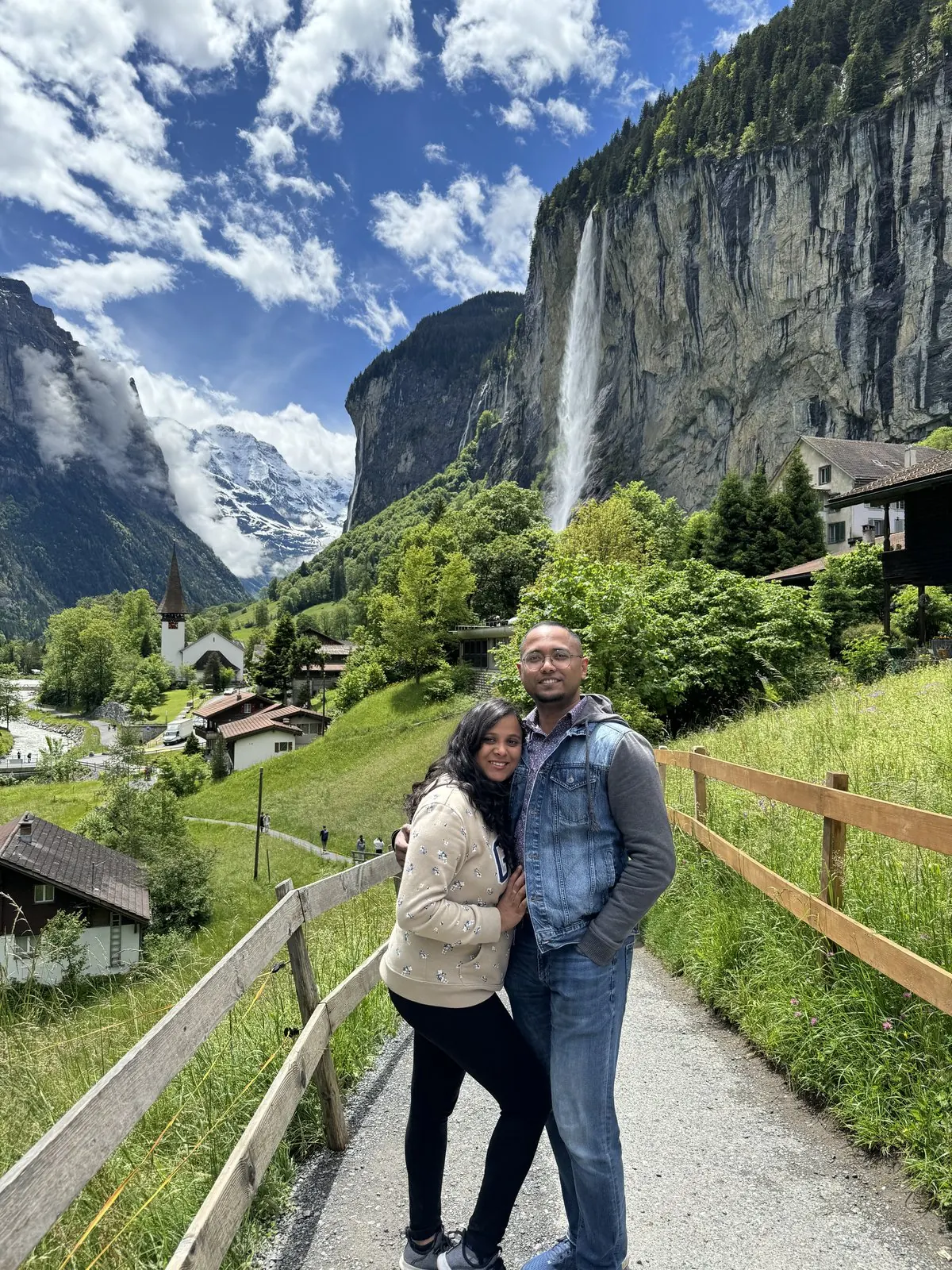 Arsha and Binu on a path above Lauterbrunnen, Staubbach Falls and the valley cliffs behind them