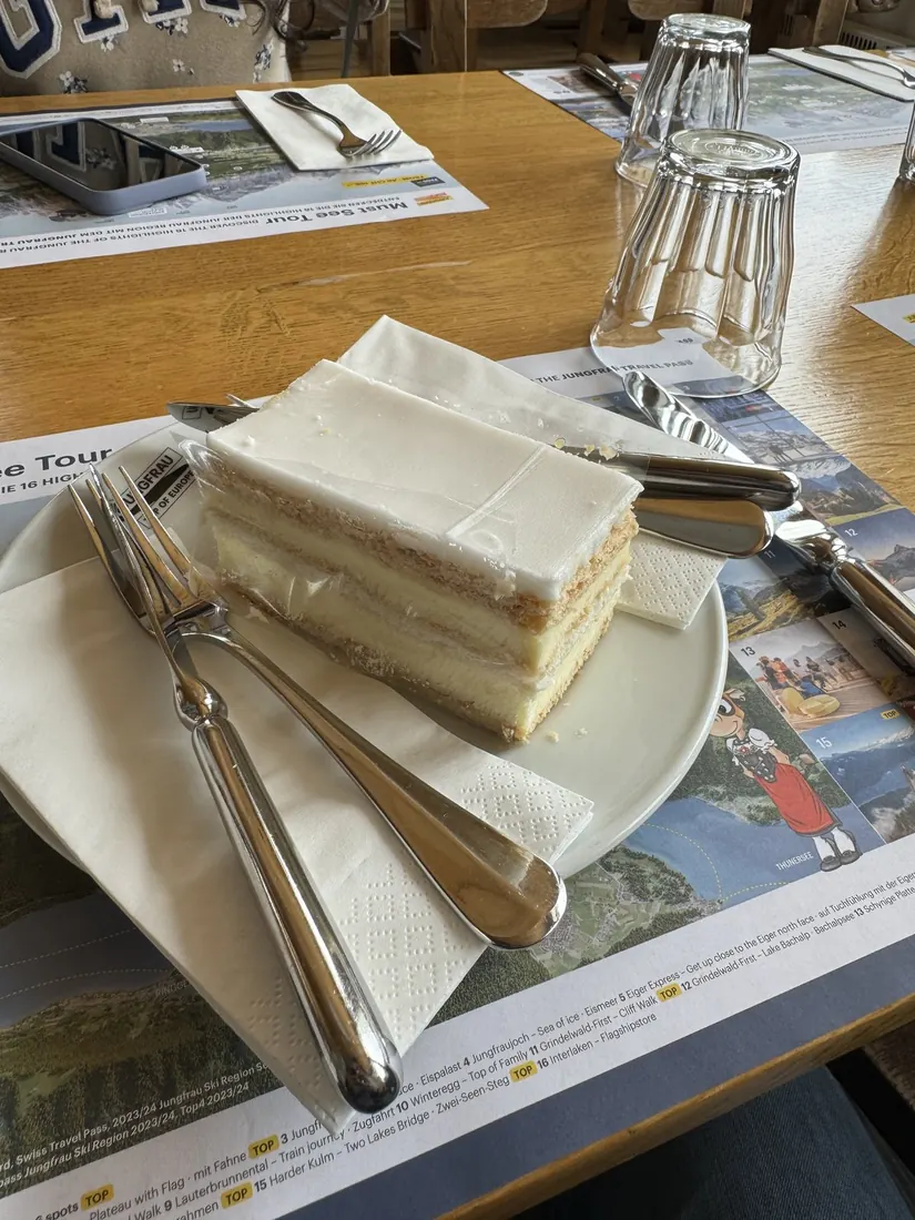 A slice of Swiss cream cake on a plate on a restaurant table