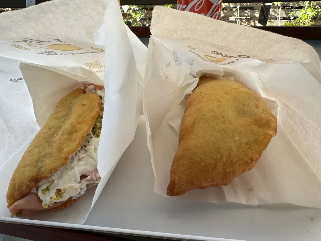 Two panzerotti in paper wrappers on an outdoor table