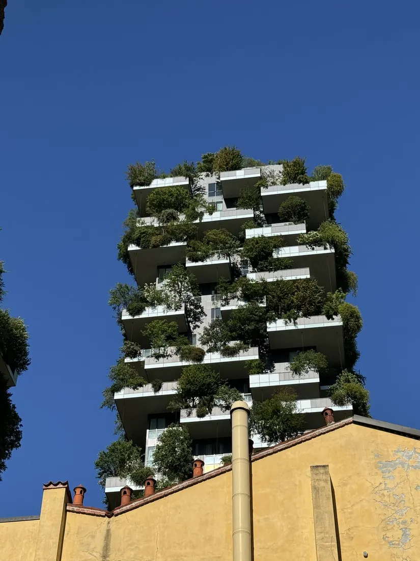 The Bosco Verticale tower covered in trees against a deep blue sky