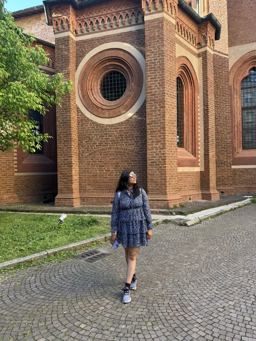 Arsha beside a red brick church with a round window in Brera