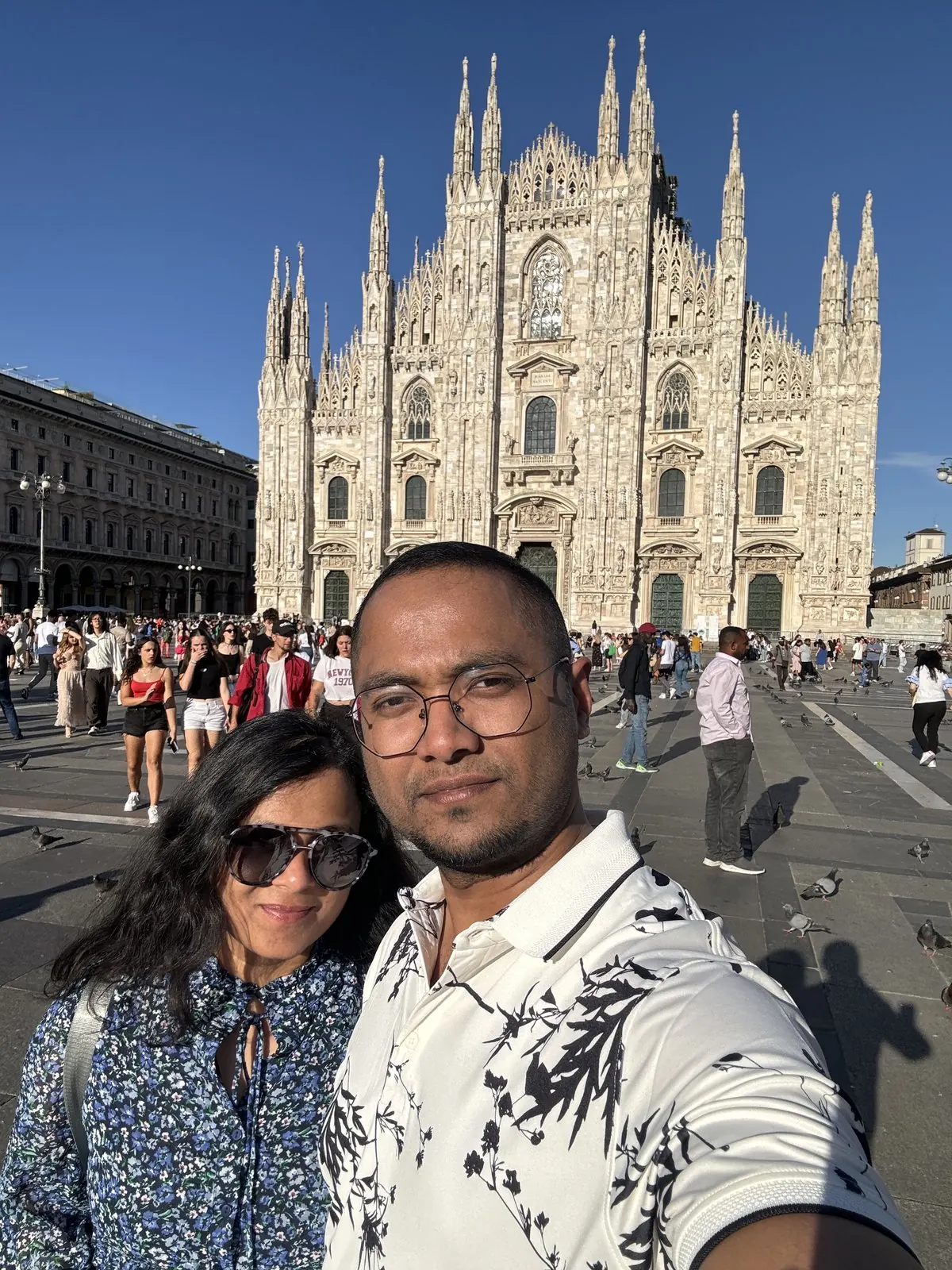 Selfie of Arsha and Binu in front of Milan's white Gothic cathedral in the evening sun