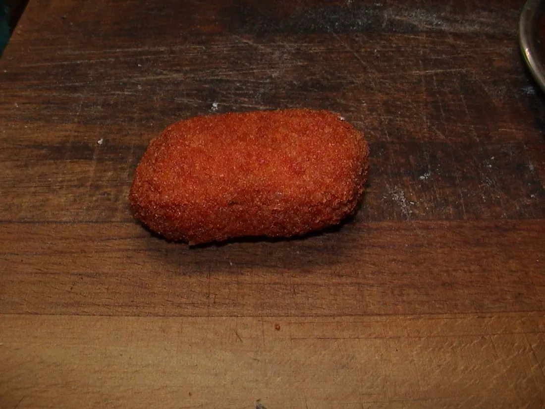 A single supplì on a worn wooden board